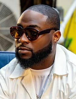 Davido wearing high-contrast electric brights paired with sharp tailoring, showcasing ultra violet, neon fuchsia, electric jade, polished pewter, and onyx from the Bold Winter palette.