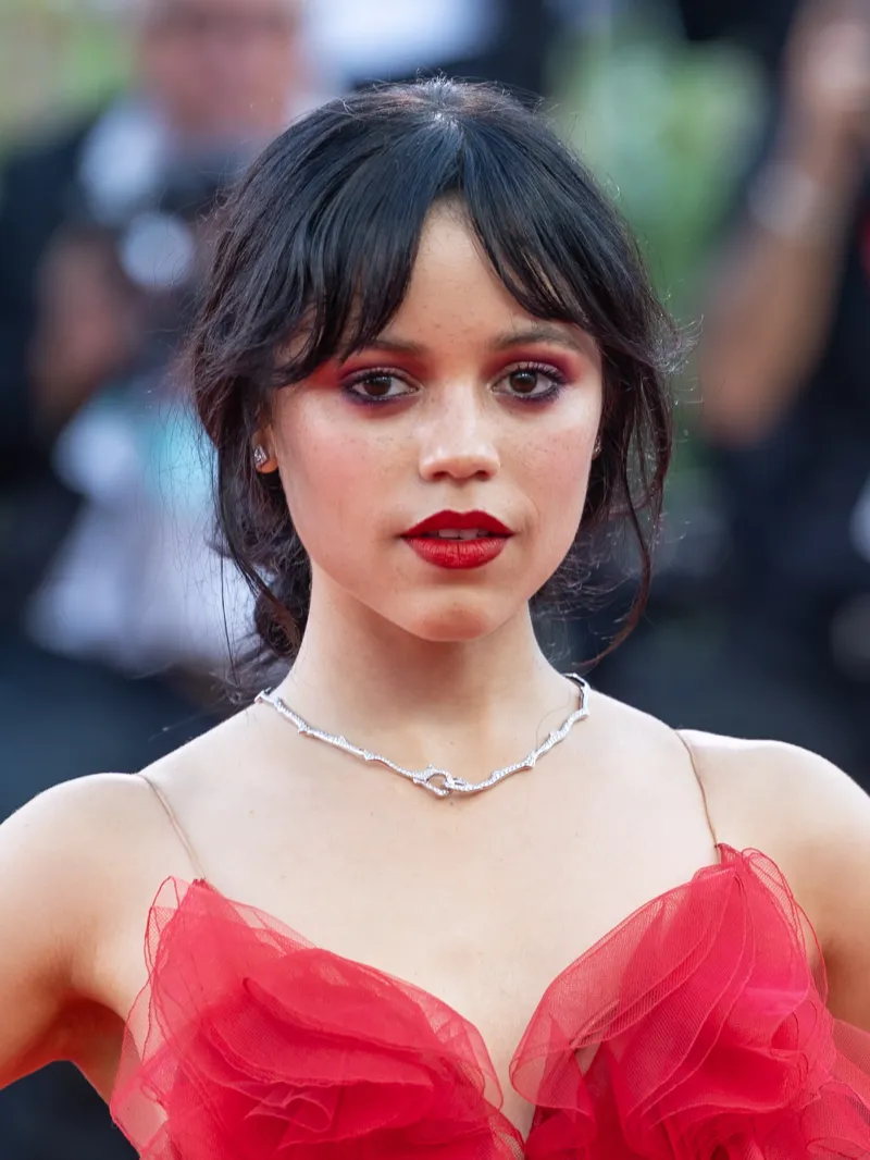 Jenna Ortega wearing deep jewel-toned ensembles with sharp contrast, showcasing ink black, deep plum, white lace, burgundy, and midnight navy from the Deep Winter palette.