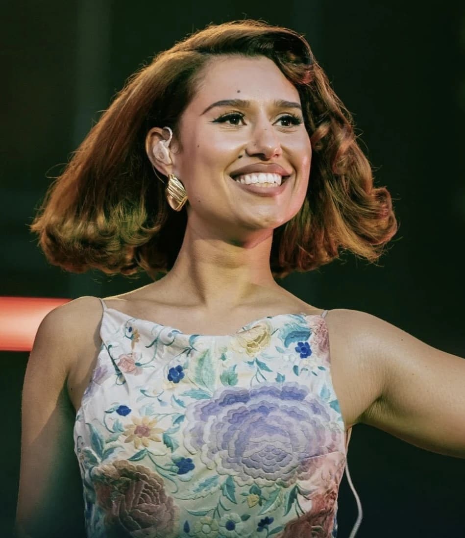 RAYE wearing luminous spring outfits with juicy warm hues, showcasing papaya orange, sunny marigold, aqua turquoise, creamy ivory, and rose gold from the Warm Spring palette.