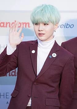 Editorial gallery of Suga (BTS) styled in bold winter ensembles mixing neon pops, inky black, and chrome sparkle, highlighting ultra violet, neon fuchsia, electric jade, polished pewter, and onyx.