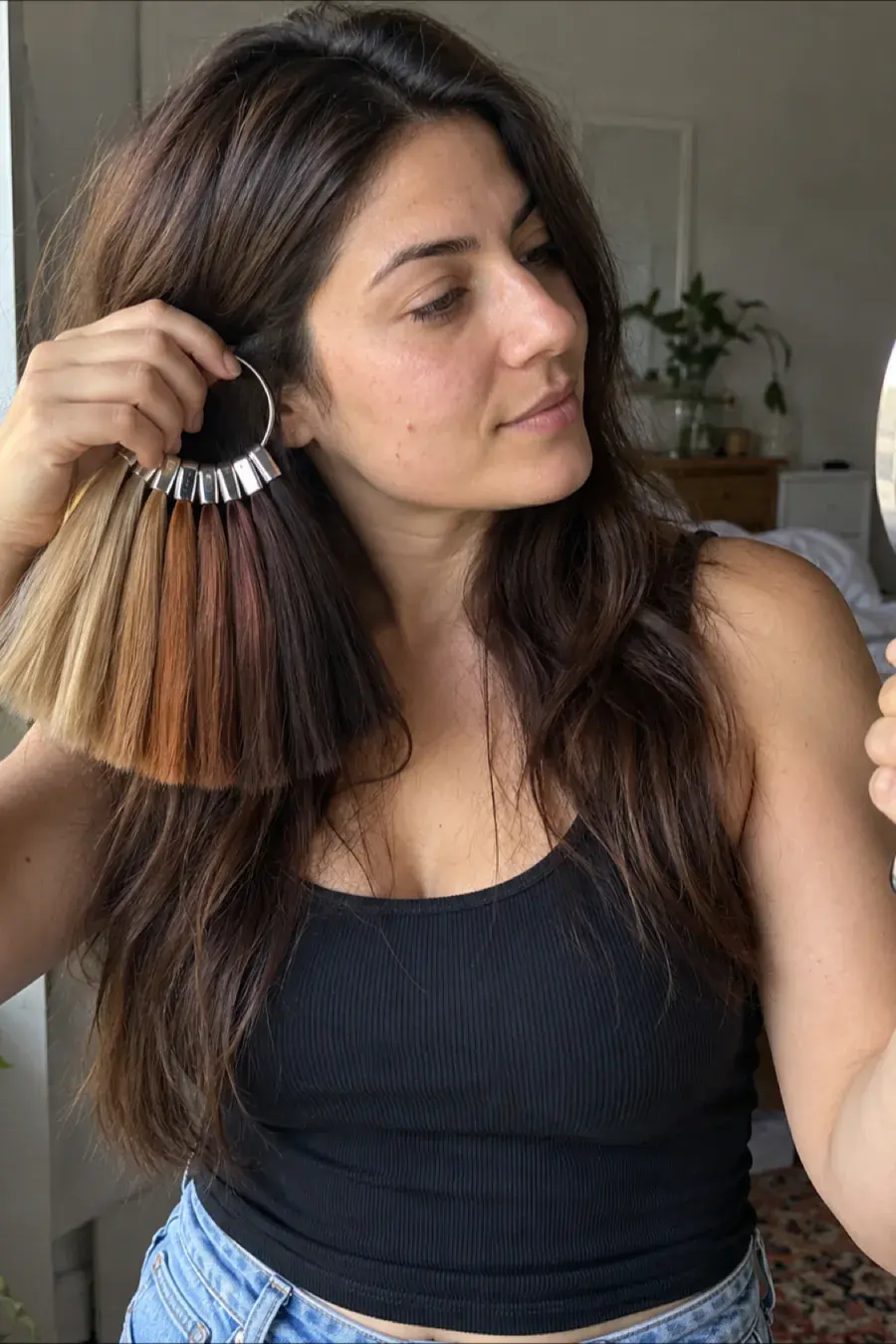 Woman comparing hair color swatch cards from ash blonde to copper to dark brown next to her face to see which hair color suits her